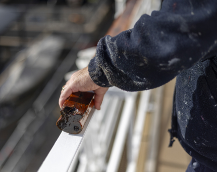 A close up of hands attaching a handrail to the railings on deck. 