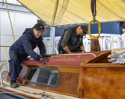 Two Maintenance men on the Royal Barge, they are sanding the roof. 