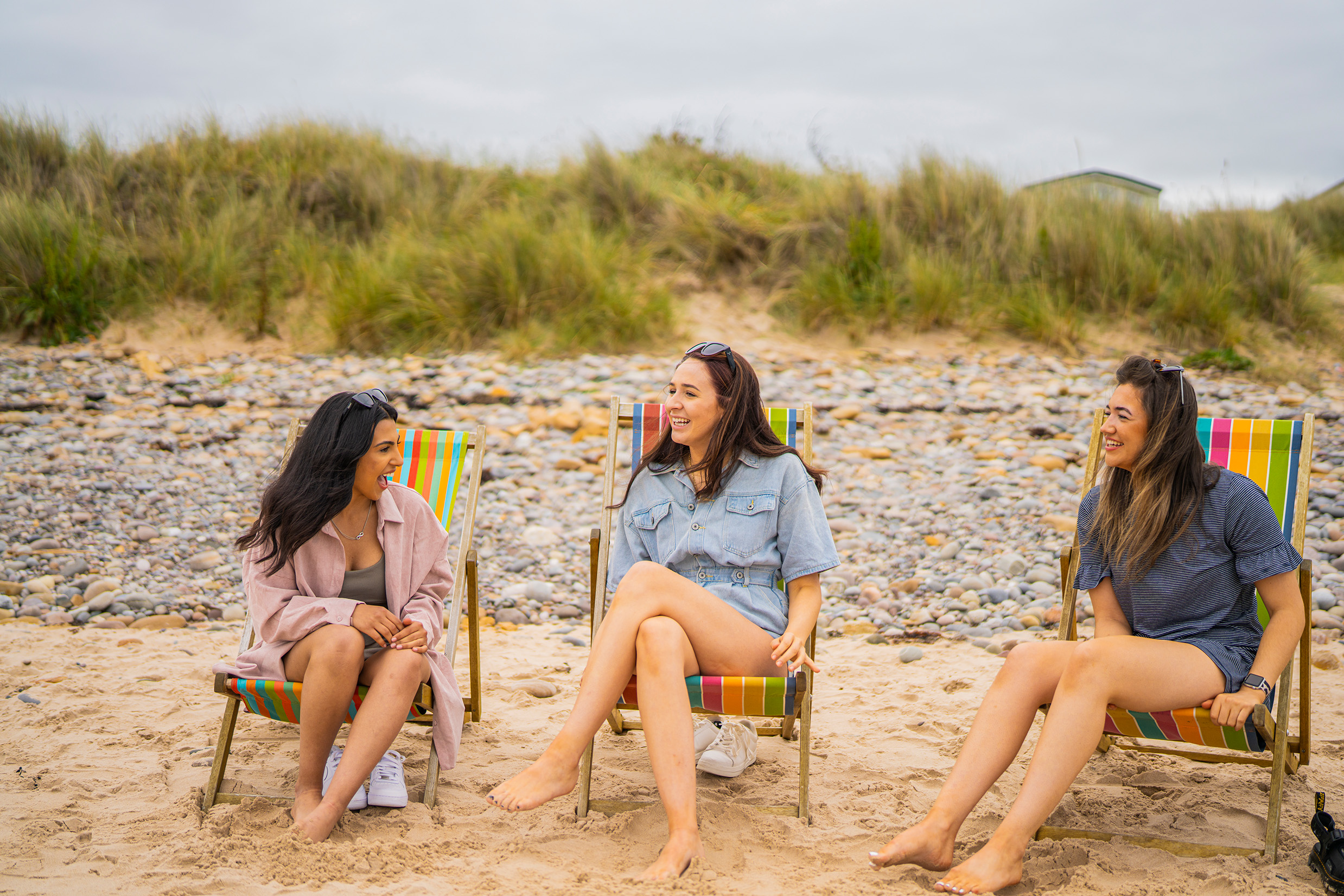 Three women sitting on chairs on the beach in Scotland