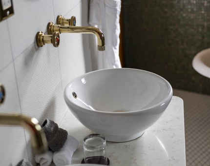 A white sink with brass tap fixtures in one of Fingal Hotel's cabins. 