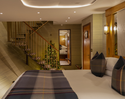 A luxury duplex cabin aboard Fingal Hotel, there is a Christmas tree next to the spiral staircase. 