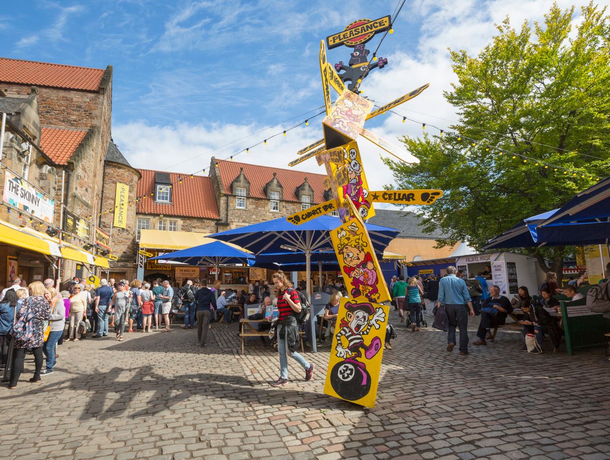 The Pleasance Courtyard at the Edinburgh Festival Fringe. There is a signpost in the middle pointing in multiple directions.