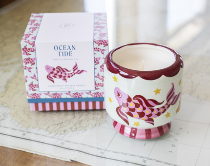 A candle in a ceramic container with a Koi fish design on it. 