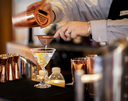 A barman preparing a cocktail in a martini glass. 