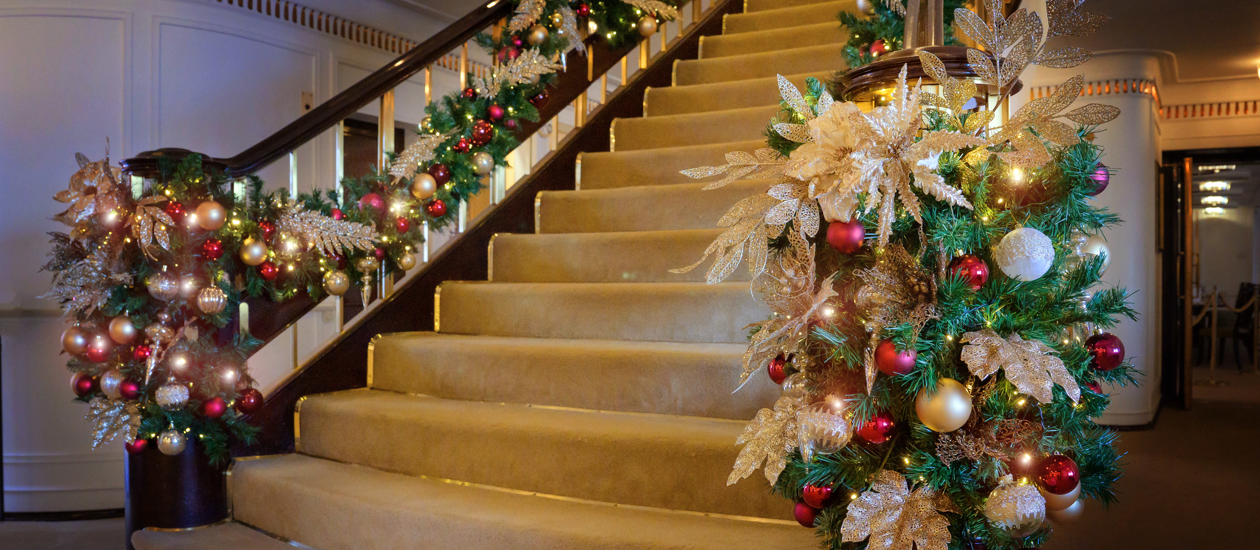 Grand staircase dressed for Christmas with green foliage, red and gold decorations