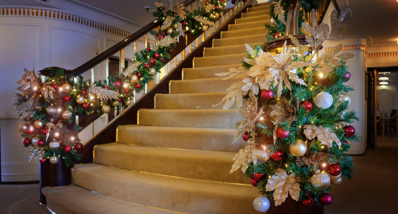 Grand staircase dressed for Christmas with green foliage, red and gold decorations