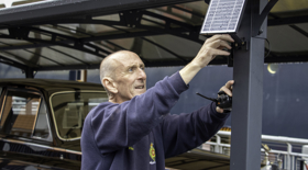 A man from the Facilities team fixing a solar panel to a post on the Rolls-Royce garage. 