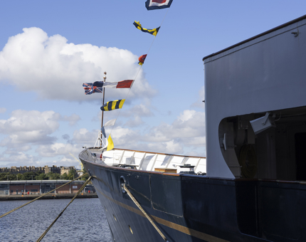 The Dress Flags flying above Britannia on a sunny day in the historic Port of Leith. 
