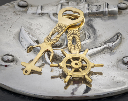 Two gold nautical-themed bottle openers. 