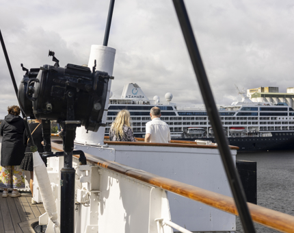 Visitors enjoying the views over the Port of Leith from the Bridge of Britannia. There is a cruise ship in the background. 