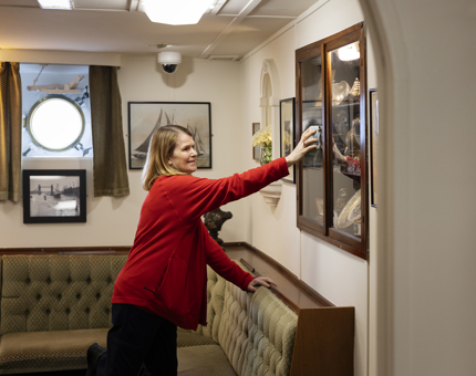 A Housekeeper is cleaning the trophy cabinet in the Warrant Officer and CPOs mess aboard Britannia. 