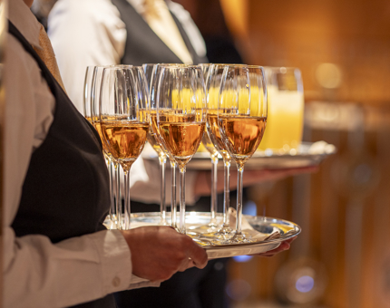 Waiters holding trays of Champagne. 