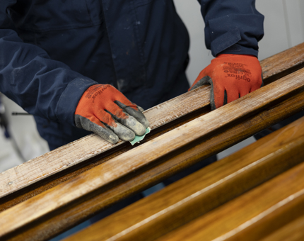 A close up of hands sanding wooden handrails. 