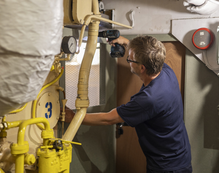 A Maintenance man is in Fingal Hotel's Engine Room and is fixing a door. 