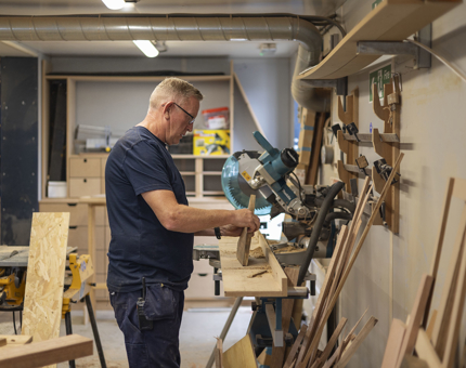 In the Joiner's Workshop, a maintenance man is cutting wood.