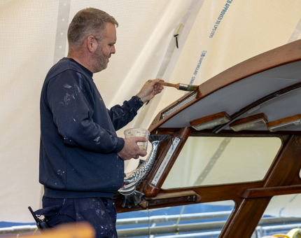 A maintenance team member is varnishing the Royal Barge. 
