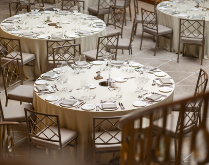 Round tables set for an event in Fingal Hotel's Ballroom in Leith. The tables have cream table cloths. 
