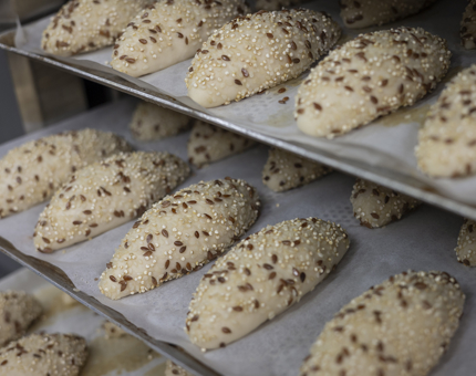 Trays of seeded bread rolls waiting to be baked in the oven. 