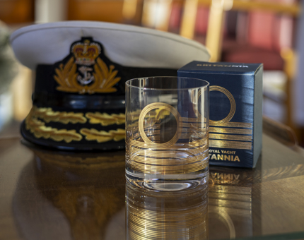 A Britannia Admiral patterned glass tumbler. There is a Captain's hat behind it. 