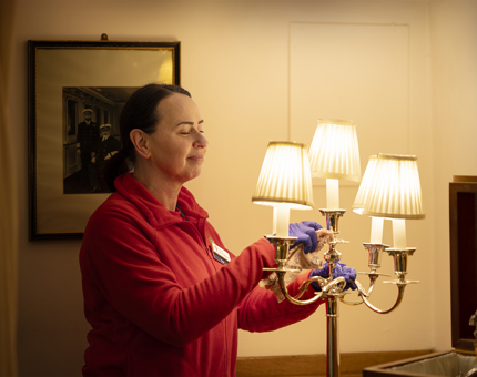 A Housekeeper is polishing a silver candelabra aboard Britannia. 
