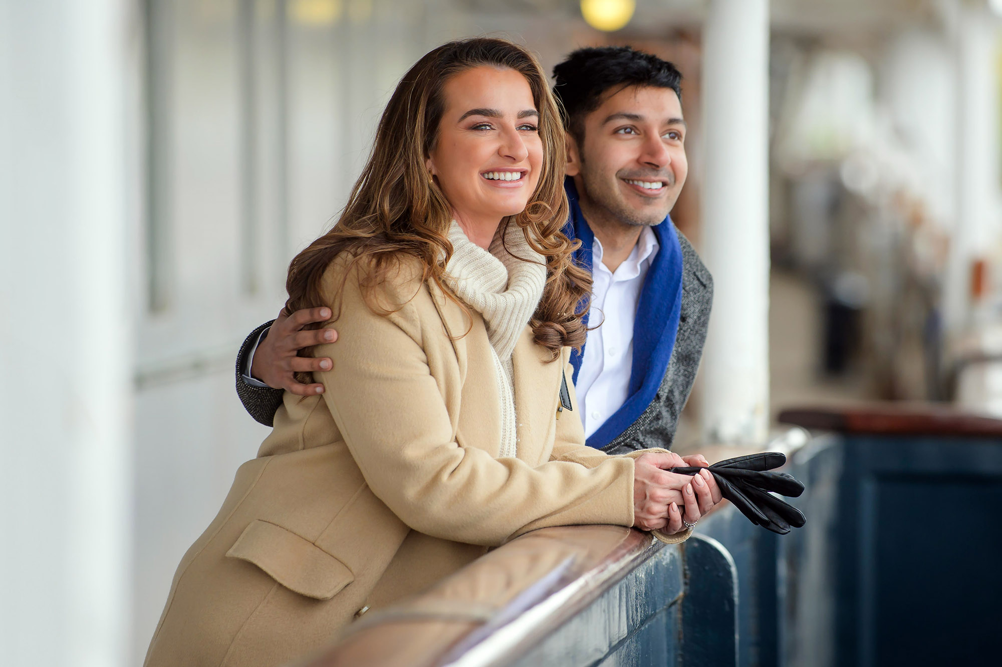 A woman and a man leaning over a handrail outside on deck at The Royal Yacht Britannia. 