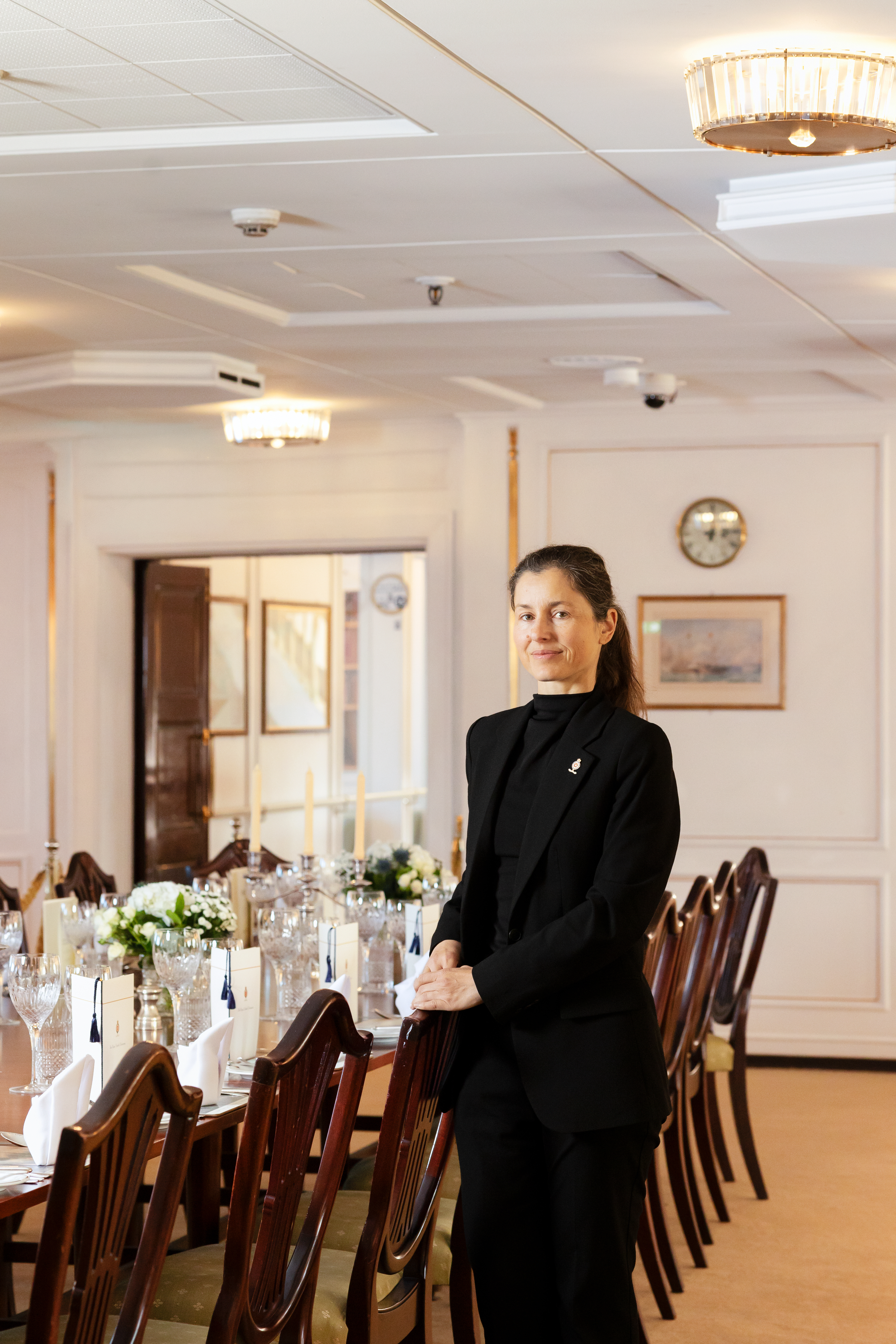 A woman standing at a dining table for a portrait 