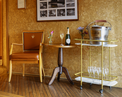 Fingal Hotel's Reception area, there is a brown chair, next to it is a small table and drinks trolley with Champagne. 