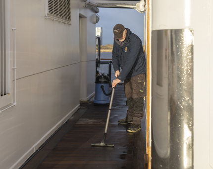 A Maintenance man removing water from the deck after heavy rain. 