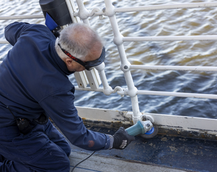A maintenance man is grinding old layers of paint off in preparation for repainting. 