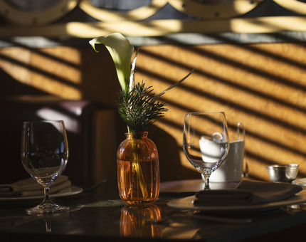 A table in The Lighthouse Restaurant with an orange vase on it. 