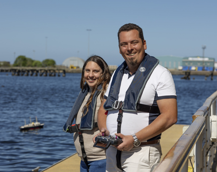 A man and woman wearing life jackets standing on Britannia's pontoon.