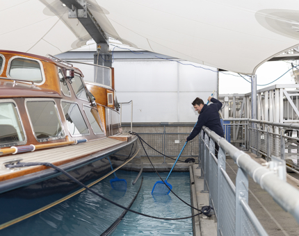 A man is using a net to clean the pond next to the Royal Barge, The Royal Yacht Britannia. 