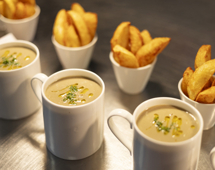 Three mugs of mushroom soup and four bowls of potato wedges are on the bench in the Galley, ready to be served.  