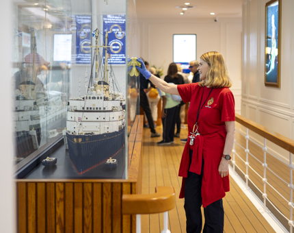 A Housekeeper is cleaning a case that contains a model of Britannia made out of Lego in the Visitor Centre. 