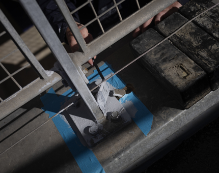 A close up of a hand holding a paintbrush adding a coat of silver paint to metal work at the Royal Barge's pond. 