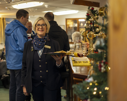 A Visitor Assistant is holding a tray of shortbread to offer to visitors. 