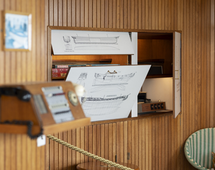 A close up of a wood paneled wall in the Sun Lounge, there is a games cabinet and a phone. 