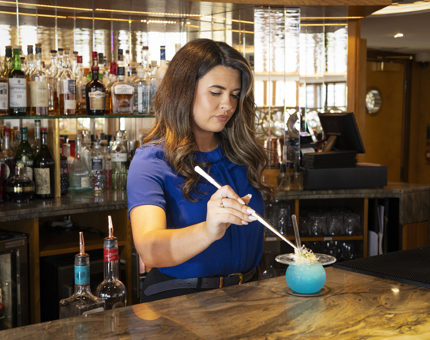 A member of the bar staff is adding a finishing touch to a cocktail. 