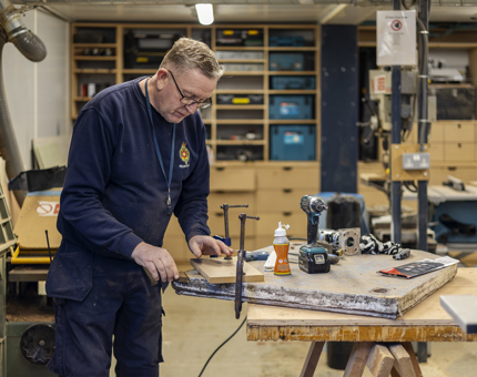 A Maintenance team member cutting pieces of wood in the workshop. 