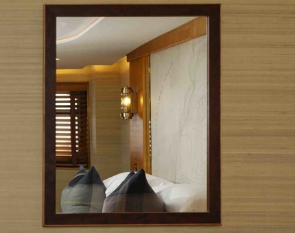 A mirror on the wall shows a reflection of a bed and headboard in one of Fingal Hotel's cabins. 