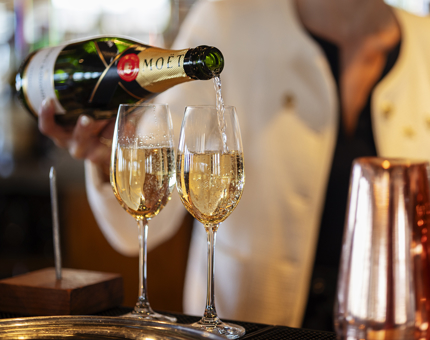 A woman pouring two glasses of Moet and Chandon Champagne. 