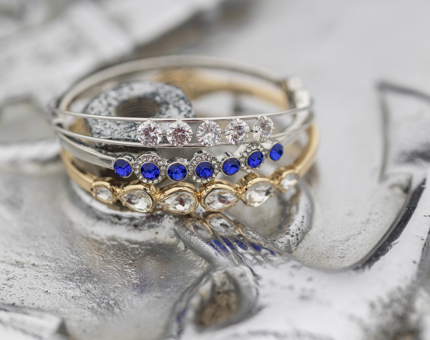 Three bracelets stacked upon each other, they have clear and blue gems on them. 