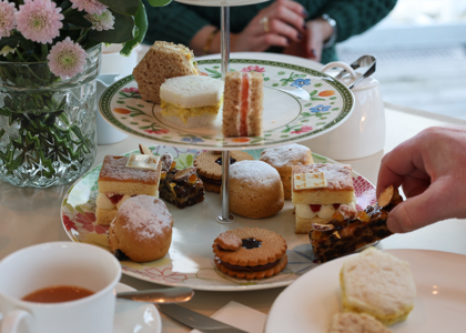 A Hand Is Reaching For A Cake From A Cake Stand In The Royal Deck Tearoom On The Royal Yacht Britannia.