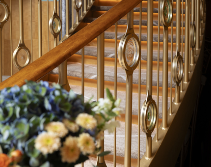 A close up of a staircase in Fingal's Ballroom. The railings are gold in colour with round glass details. 