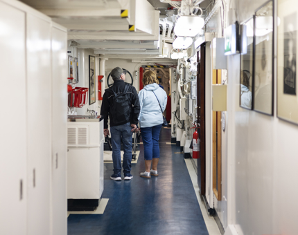 Two people walking down a hallway aboard Britannia.  