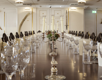 The long table in the State Dining Room is set for a dinner. There are candelabras in the middle of the table. 
