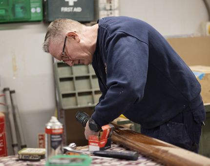 A maintenance team member adding brass ends to handrails. 