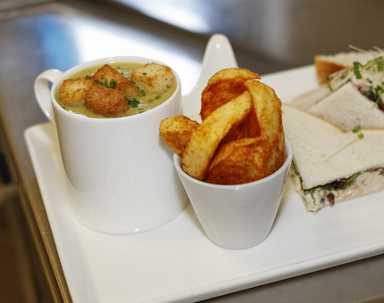 A mug of soup, bowl of potato wedges and a sandwich on a plate, ready to be served in the Tearoom. 