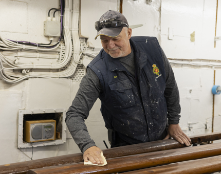 A Maintenance man sanding handrails.
