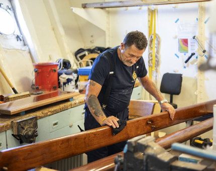 A Maintenance man wiping down a handrail with a cloth. 
